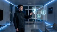 Young Caucasian businessman in dark suit interacting with futuristic holographic security interface in modern office with blue LED lighting and glass walls.