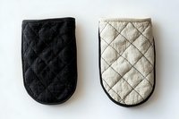 Pair of quilted oven mitts in black and cream with diamond stitching pattern, isolated on white background, ready for kitchen product design and e-commerce use.