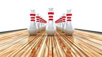 Bowling pins arranged on wooden lane with red stripes, ready for game night entertainment at sports facility.