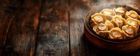 Traditional dumplings filled with meat in rustic ceramic bowl on dark wooden table with copy space, moody food photography background.