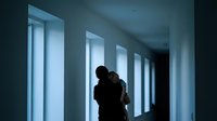 Silhouette of couple embracing in modern corridor with dramatic window lighting creating romantic atmosphere for relationship and love concepts.