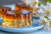 Caramel flan dessert on blue plate with fresh jasmine flowers, close up view showing translucent texture and golden brown color. Sweet culinary background.
