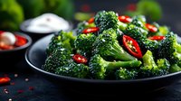 Fresh steamed broccoli florets with red chili peppers on dark plate, healthy green vegetable side dish for nutritious meals and cooking recipes.