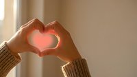 Hands forming heart shape with warm sunlight glow, expressing love and affection for Valentine's Day, wedding, and romantic greeting card designs.