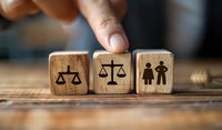 Wooden dice with legal justice scales and gender equality symbols arranged by hand, perfect for law firm marketing, civil rights concepts, and social justice themes.