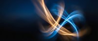Abstract flowing light trails in blue and orange creating dynamic energy waves on dark background for modern digital design and technology concepts.