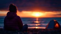 Woman in purple jacket watching dramatic ocean sunset with camping tent glowing orange against darkening sky and waves, creating peaceful outdoor scene.