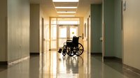 Empty wheelchair in modern hospital corridor with bright lighting and clean floors for healthcare and medical facility concepts.