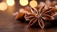 Star anise pods on rustic wooden surface with soft golden bokeh lights in background, macro food photography highlighting natural spice texture and aromatics.