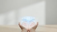 Cupped hands holding glowing digital hologram sphere with network connections on neutral background for technology and innovation concepts.