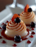 Elegant meringue swirls topped with fresh blueberries and orange segments, drizzled with raspberry sauce on white plate, macro food photography for dessert menu.