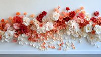 Delicate paper flowers in coral, red, and white create an elegant floral arrangement border against white background, showcasing intricate craftsmanship and romantic design.