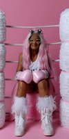 Senior woman with pink hair wearing boxing gloves, cat ears, glasses and furry boots poses playfully against pink background, embodying joyful aging and vitality.