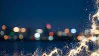Water splashes with bokeh city lights at night creating magical urban waterfront scene with sparkling droplets and colorful light reflections.