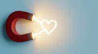 Red horseshoe magnet attracting glowing heart shape on blue background. Concept for love attraction, romance magnetism, relationship power, dating success.