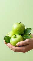Fresh green apples with water droplets held in hands against pale green background, symbolizing healthy eating and organic produce.