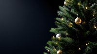 Decorated Christmas tree with gold ornaments and warm lights against dark background, creating festive holiday atmosphere.