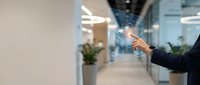 Young professional man in business attire interacting with digital holographic interface displaying data visualization and network connections in modern office environment.