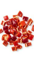 Freshly chopped red bell pepper pieces scattered on white background, showing vibrant color and texture for food and cooking content.