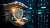 Hands protecting glowing digital shield with security icons and data streams against blurred technology background for cybersecurity concepts.