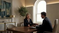 Business woman and man in formal attire having professional meeting at wooden table in modern office with arched window and contemporary decor.