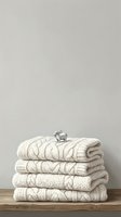 Stack of cream cable knit sweaters with decorative silver elephant ornament on top, displayed on wooden surface against neutral wall background for home decor and fashion styling.