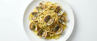 Spaghetti alle vongole with fresh clams and garlic sauce served on white plate, overhead view for restaurant menus and food blogs.