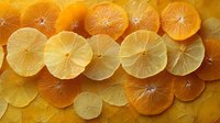 Fresh citrus orange and lemon slices arranged in overlapping pattern creating bright sunny background with natural translucent texture and juicy appearance.