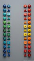 Colorful polyhedral gaming dice collection arranged in rainbow gradient from blue to red on gray background for tabletop RPG and board game enthusiasts.