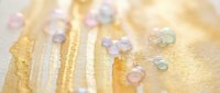 Colorful gemstones scattered on golden textured surface with warm lighting creating luxury jewelry and precious stone collection display for design projects.