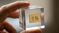 Hand holding transparent glass cube with one percent symbol for business growth and minimal improvement concepts.