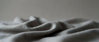 Soft gray fabric with gentle folds and wrinkles creating elegant textile waves. Luxurious material surface with natural draping for fashion design projects.