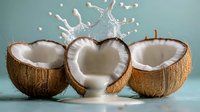 Fresh coconut halves with splashing coconut milk creating dynamic droplets against soft blue background for healthy tropical food concepts.