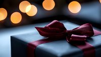 Elegant gift box with burgundy ribbon bow against warm bokeh lights background for holiday celebrations and special occasions.