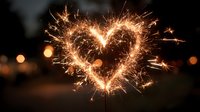 Sparkler heart shape glowing with golden sparks against dark background. Romantic celebration concept for Valentine's Day, wedding, anniversary events.
