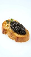 Toasted bread slice topped with luxurious black caviar and fresh microgreens on white background. Gourmet appetizer for fine dining, catering, restaurant menus, and food photography.