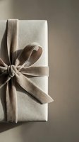 Elegant gift box wrapped in neutral beige paper with a soft velvet ribbon bow, styled in warm natural light for luxury holiday or celebration concepts.