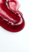 Red glossy liquid swirl with flowing motion on white background for cosmetic beauty skincare product design and advertising materials.