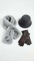Winter fashion accessories set with gray fur scarf, dark felt hat and brown leather gloves arranged on white background for seasonal style concepts.