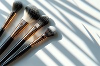 Professional makeup brushes with rose gold ferrules on white background with natural window shadow overlay, perfect for beauty and cosmetic industry content.