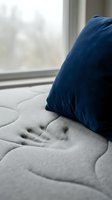 Cozy window seat with navy blue velvet cushion resting on gray quilted fabric, soft natural light streaming through glass pane, ideal for home decor, interior design, and lifestyle content.