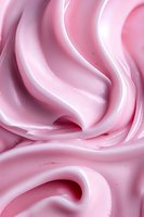 Smooth swirls of pink cream create soft waves and curves, highlighting delicate texture and glossy surface suitable for cosmetic and food industry backgrounds.
