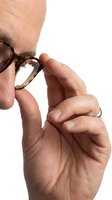 Close-up of mature male hand adjusting tortoiseshell eyeglasses against white background. Man wearing optical frames for vision correction and eye care needs.