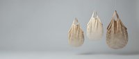 Three natural woven mesh shopping bags hanging against neutral background, sustainable zero waste lifestyle concept for eco-friendly retail design.