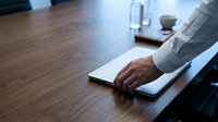 Professional businessman hand on laptop keyboard at wooden desk in modern office workspace for corporate productivity and business technology solutions.