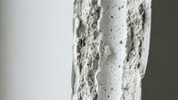 White textured wall surface with rough plaster finish and small holes, showing architectural detail and interior design element for modern construction.