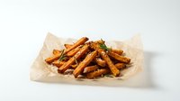 Golden crispy sweet potato fries seasoned with herbs served on parchment paper, perfect for restaurant menus and food photography projects.