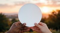 Hands holding white circle with sunset landscape background, representing ideas, communication, or environmental concepts for design and marketing projects.