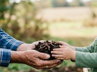 Adult male and child holding rich soil together in hands outdoors, representing environmental education, sustainable farming, and ecological responsibility for agricultural and conservation projects.