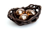 Metallic copper spheres nestled in dark twisted driftwood bowl against white background, modern organic home decor composition isolated for design use.